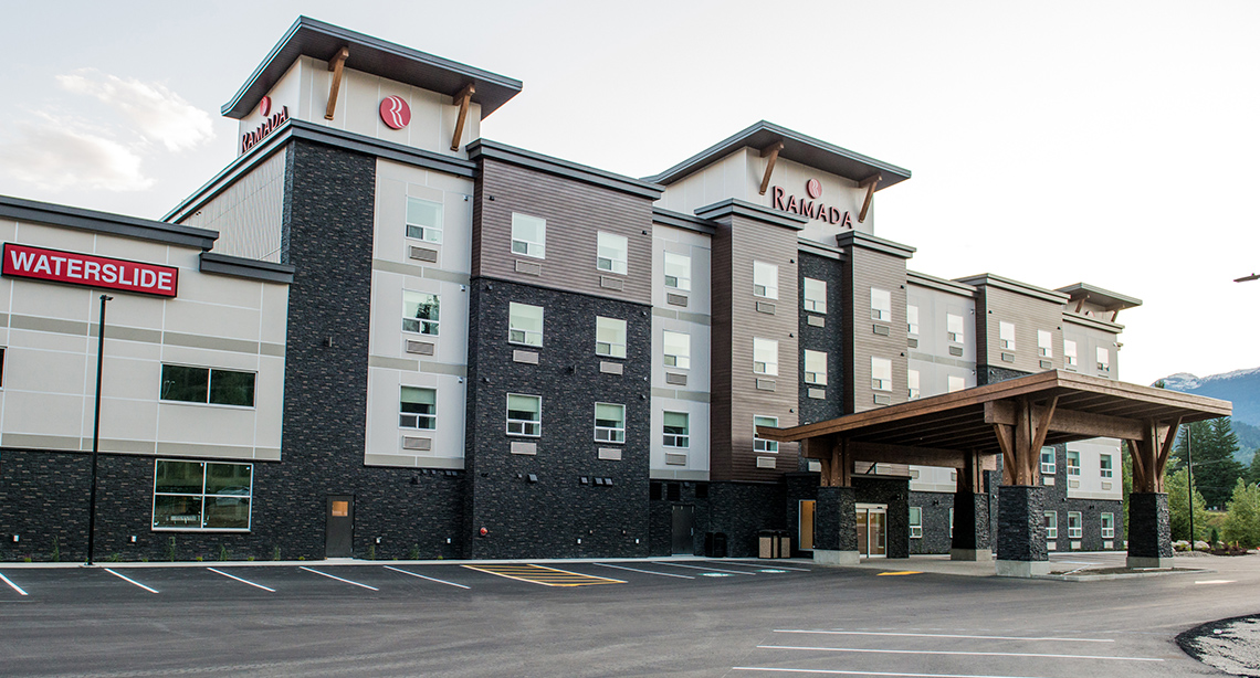 Four story hotel with stone accents and large wood clad structure over passenger drop off area